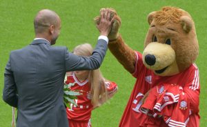 Der Trainer Pep Guardiola steht am 24.06.2013 bei seiner Vorstellung als neuer Trainer des Fußball-Bundesligisten FC Bayern München in der Allianz Arena in München (Bayern) mit Maskottchen Bernie auf dem Rasen. Foto: Peter Kneffel/dpa +++(c) dpa - Bildfunk+++