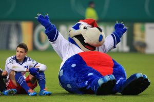 ARCHIV - Fußball DFB-Pokal Achtelfinale: Hamburger SV - 1. FC Köln am 03.12.2013 in der Imtech Arena in Hamburg. Hamburgs Ivo Ilicevic sitzt nach dem Spiel neben HSV Maskottchen «Hermann» auf dem Rasen. Der Hamburger SV ist noch nie aus der Bundesliga abgestiegen. Foto: Christian Charisius/dpa +++(c) dpa - Nachrichten für Kinder+++
