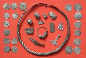 Teile des Silberschatzes von Schaprode mit gewendeltem, verschliessbarem Drahtring, Silberperlen mit Granulationsauflage, zerhacktem Silberschmuck, Thorshammeramulett und dänischen sowie ottonischen Münzen. (Foto: dpa)