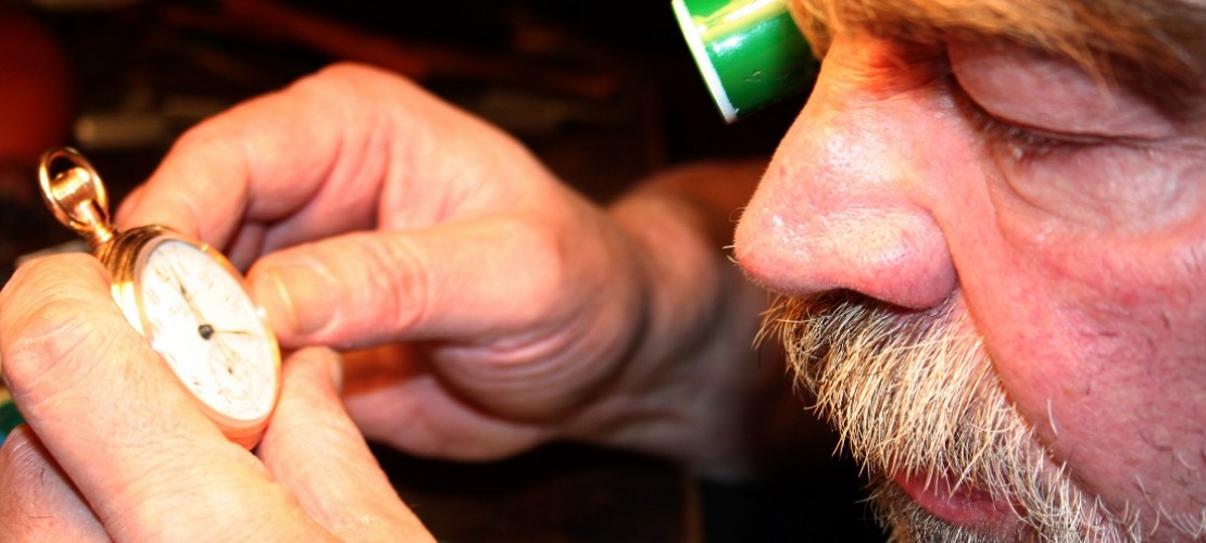 Mit einer Lupe auf dem Auge begutachtet Herr Bischoff eine Taschenuhr. (Foto: dpa)