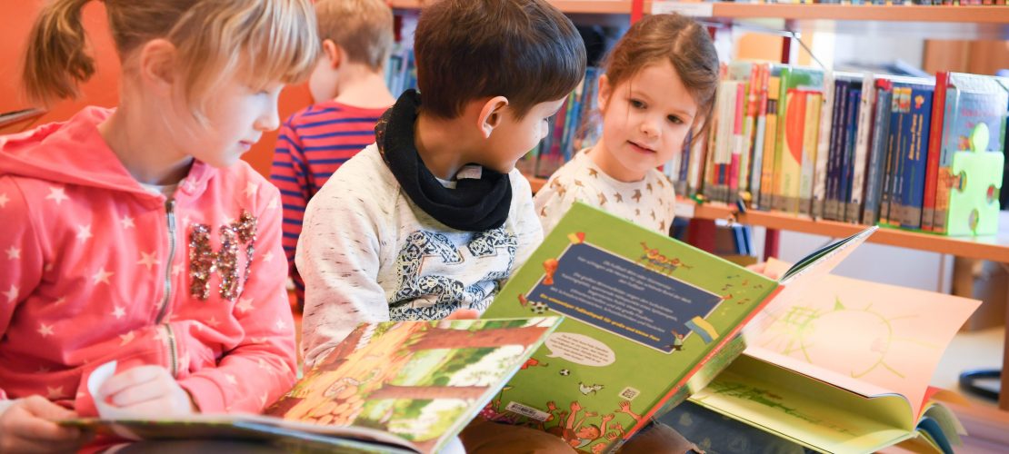 Kinder schauen sich Bücher an. (Foto: dpa)