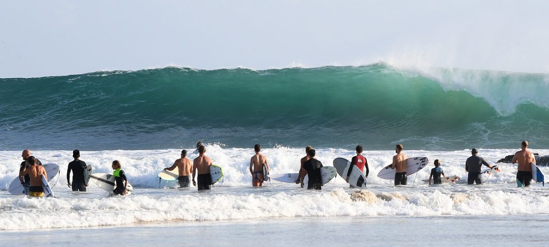 17.02.2018, Australien, Queensland, Gold Coast: Wellenreiter stehen nahe den Snapper Rocks vor der Brandung. Die großen Wellen des Pazifik an der Ostküste sind auch ein Ergebnis des Tropen-Sturms Gita, der vor wenigen Tagen auf den Inseln von Tonga Zerstörungen anrichtete. Surfer freuten sich über hohe Wellen an der Ostküste von Australien. ACHTUNG: Dieses Bild hat dpa auch im Bildfunk gesendet. Foto: Dave Hunt/AAP/dpa - Honorarfrei nur für Bezieher des Dienstes dpa-Nachrichten für Kinder +++ dpa-Nachrichten für Kinder +++