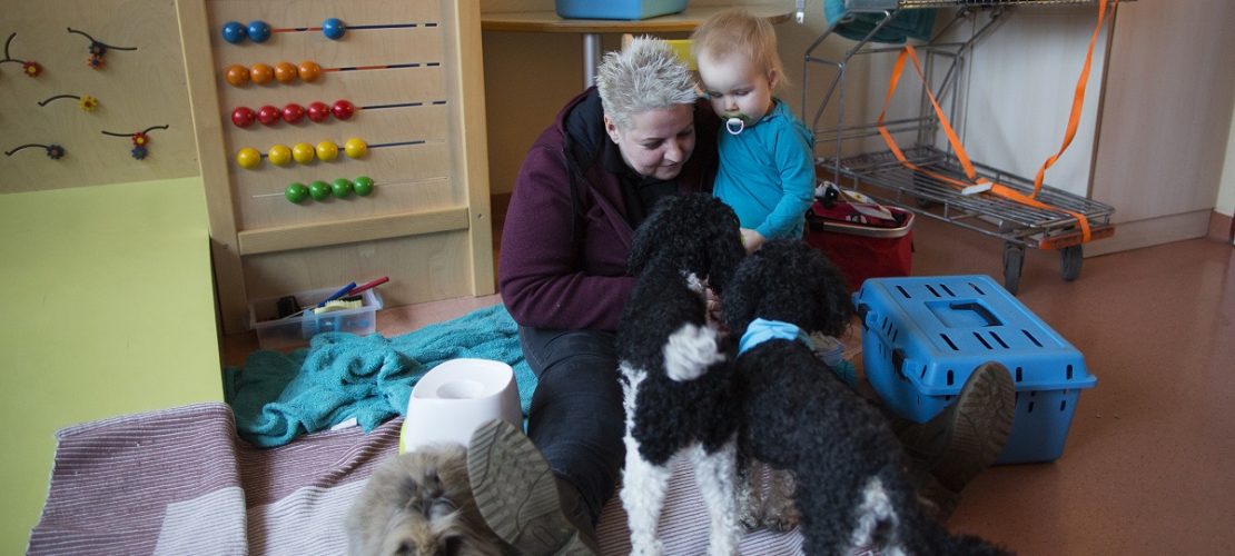 Die 43-jährige Tiertherapeutin Bianca Terhürne sitzt in der Dortmunder Kinderklinik mit der zweijährigen Maria Ost neben ihren Hunden und Kaninchen. (Foto: dpa)