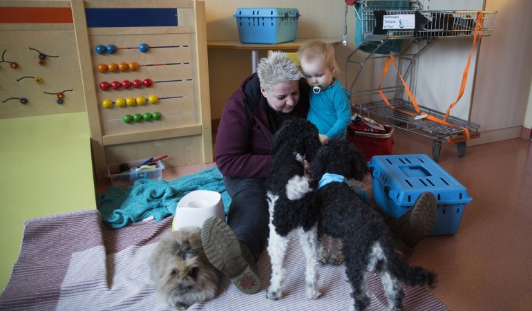 Die 43-jährige Tiertherapeutin Bianca Terhürne sitzt in der Dortmunder Kinderklinik mit der zweijährigen Maria Ost neben ihren Hunden und Kaninchen. (Foto: dpa)
