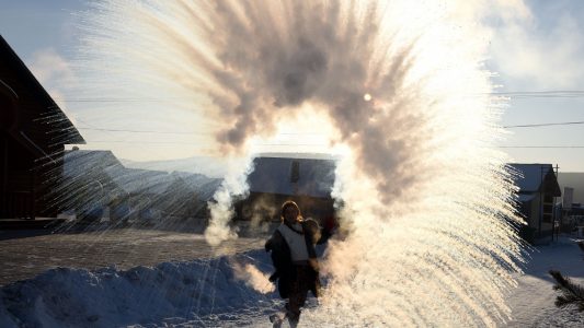 China, Mohe: Eine Touristin sprüht heißes Wasser in die Luft, das unverzüglich gefriert. Foto: Chu Fuchao/SIPA Asia via ZUMA Wire/dpa