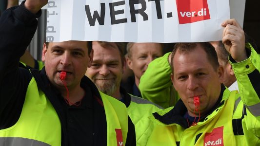 10.04.2018, Bremen: Streikende ver.di Mitarbeiter stehen vor einem Eingang zum Airport Bremen und halten Plakate mit 