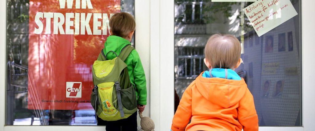 Zwei kleine Kinder stehen am 18.05.2015 an der Tür eines wegen Streik geschlossenen Kindergartens in Leipzig (Sachsen).