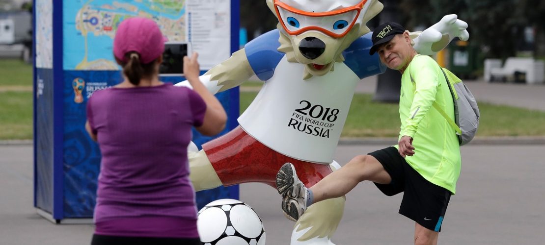 Fußballfans machen vor dem WM-Stadion mit dem Maskottchen, dem Wolf Sabiwaka, ein Erinnerungsfoto. (Foto: Lee Jin-Man/AP/dpa)