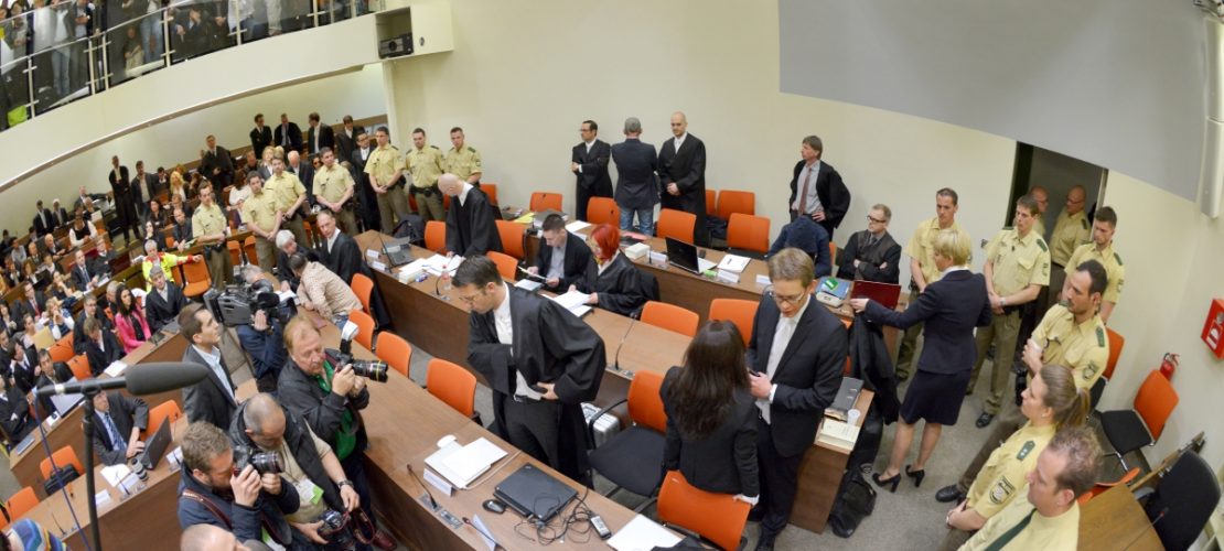 Ein Bild aus dem NSU-Prozess: Die Angeklagte Beate Zschäpe (Gruppe rechts unten in der Mitte) steht vor Beginn des Prozesses im Gerichtssaal München neben ihren Anwälten Wolfgang Stahl (l), Wolfgang Heer und Anja Sturm (r) und dreht den Zuschauern den Rücken zu. (Foto: dpa)