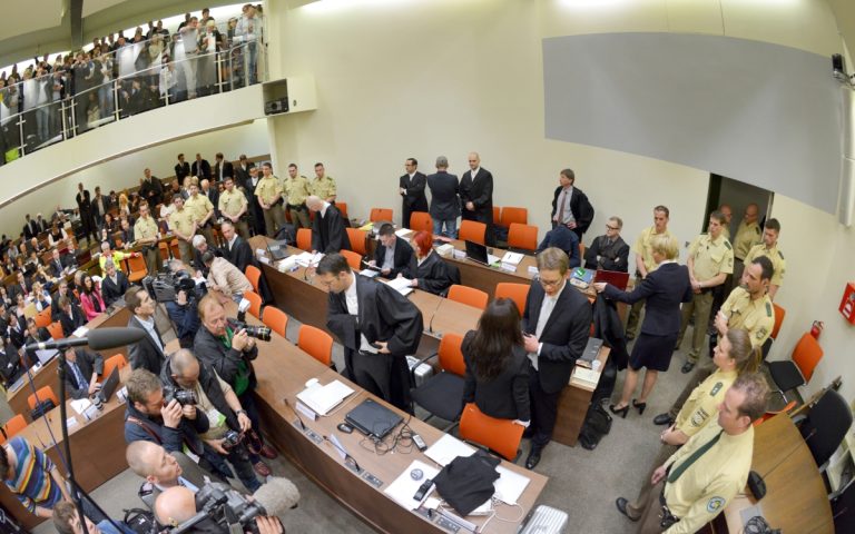 Ein Bild aus dem NSU-Prozess: Die Angeklagte Beate Zschäpe (Gruppe rechts unten in der Mitte) steht vor Beginn des Prozesses im Gerichtssaal München neben ihren Anwälten Wolfgang Stahl (l), Wolfgang Heer und Anja Sturm (r) und dreht den Zuschauern den Rücken zu. (Foto: dpa)
