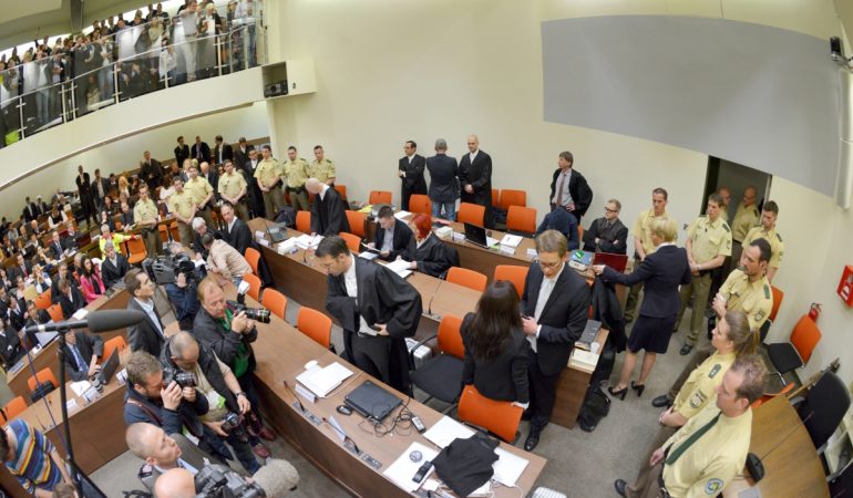 Ein Bild aus dem NSU-Prozess: Die Angeklagte Beate Zschäpe (Gruppe rechts unten in der Mitte) steht vor Beginn des Prozesses im Gerichtssaal München neben ihren Anwälten Wolfgang Stahl (l), Wolfgang Heer und Anja Sturm (r) und dreht den Zuschauern den Rücken zu. (Foto: dpa)